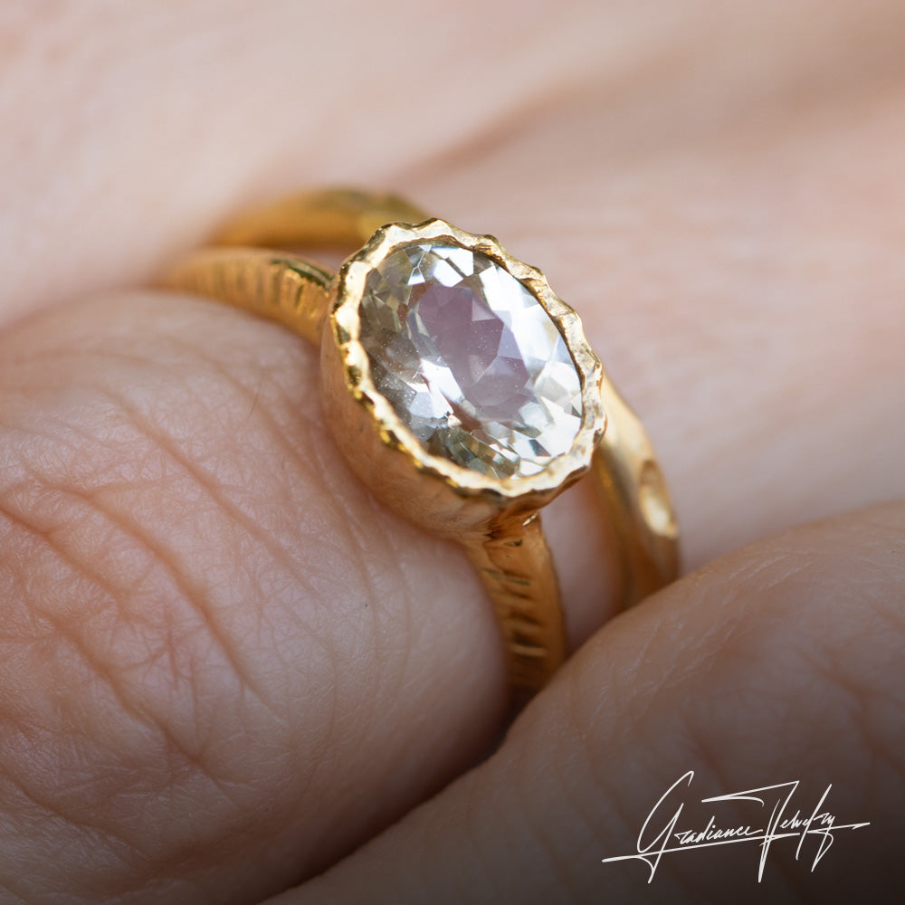 Gradiance Jewelry women's ring featuring an oval faceted Champagne Oregon Sunstone set in a 14KT yellow gold textured knife-edge band shown with the 14KT yellow gold Organic Stacking Band - shown worn.