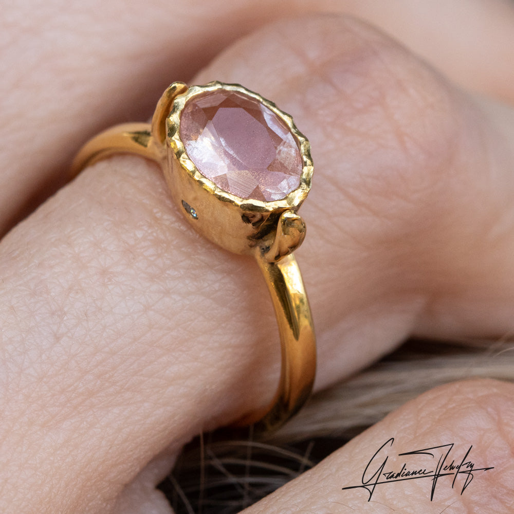 Gradiance Jewelry Sun Chaser Collection: women's 14KT yellow gold Rose ring featuring an oval Oregon Sunstone with schiller effect, accented by two diamonds and a leaf design, displayed on a finger- alternate shot.