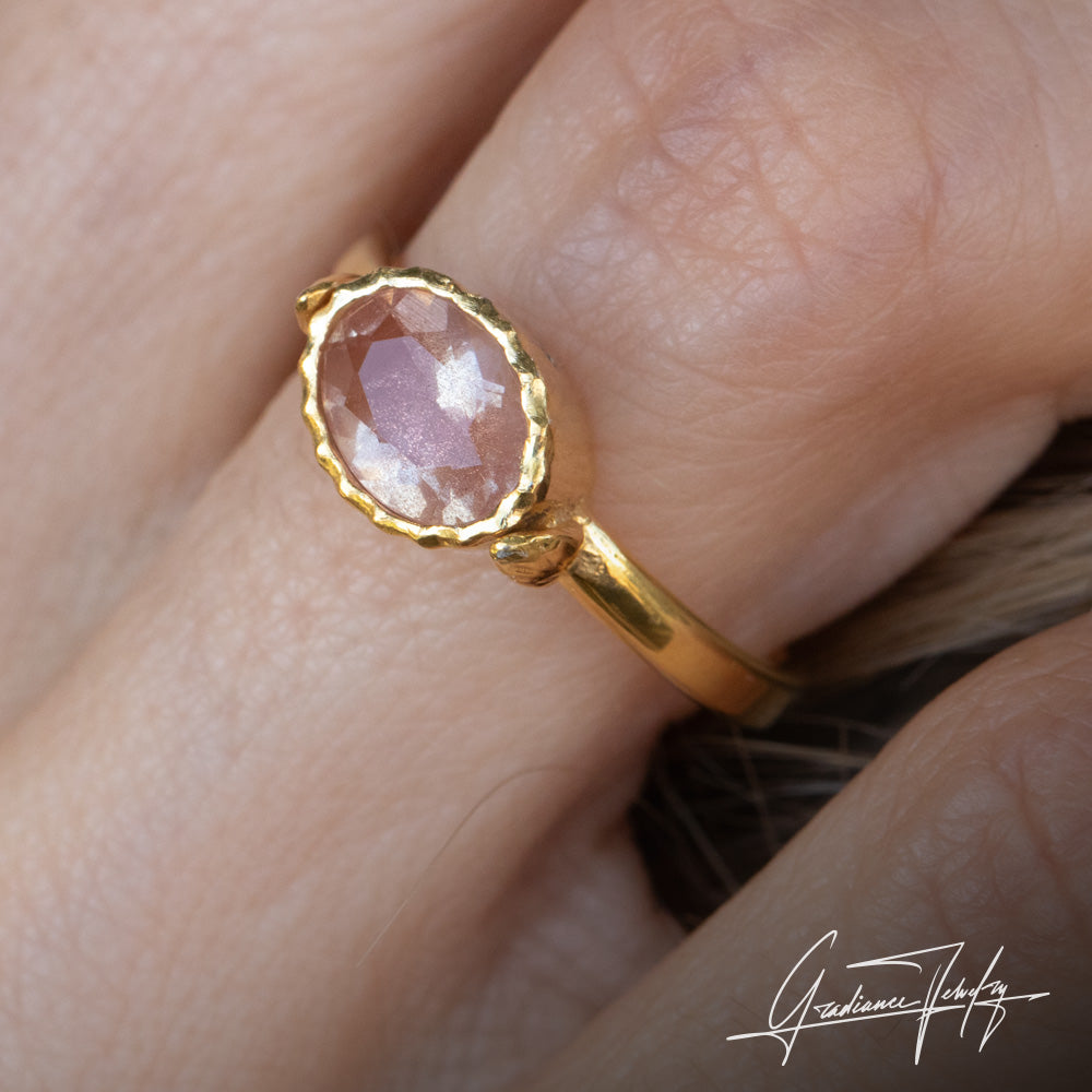 Gradiance Jewelry Sun Chaser Collection: women's 14KT yellow gold Rose ring featuring an oval Oregon Sunstone with schiller effect, accented by two diamonds and a leaf design, displayed on a finger