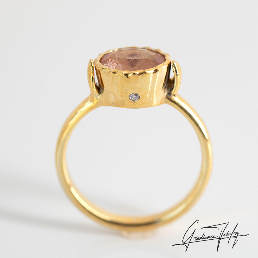 Gradiance Jewelry Sun Chaser Collection: women's 14KT yellow gold Rose ring featuring an oval Oregon Sunstone with schiller effect, accented by two diamonds and a leaf design, diamond view side view.