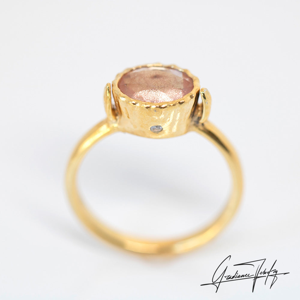 Gradiance Jewelry Sun Chaser Collection: women's 14KT yellow gold Rose ring featuring an oval Oregon Sunstone with schiller effect, accented by two diamonds and a leaf design, diamond view.