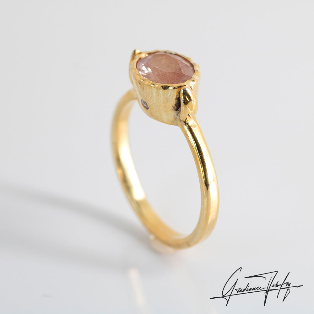 Gradiance Jewelry Sun Chaser Collection: women's 14KT yellow gold Rose ring featuring an oval Oregon Sunstone with schiller effect, accented by two diamonds and a leaf design, product shot from an alternate side.