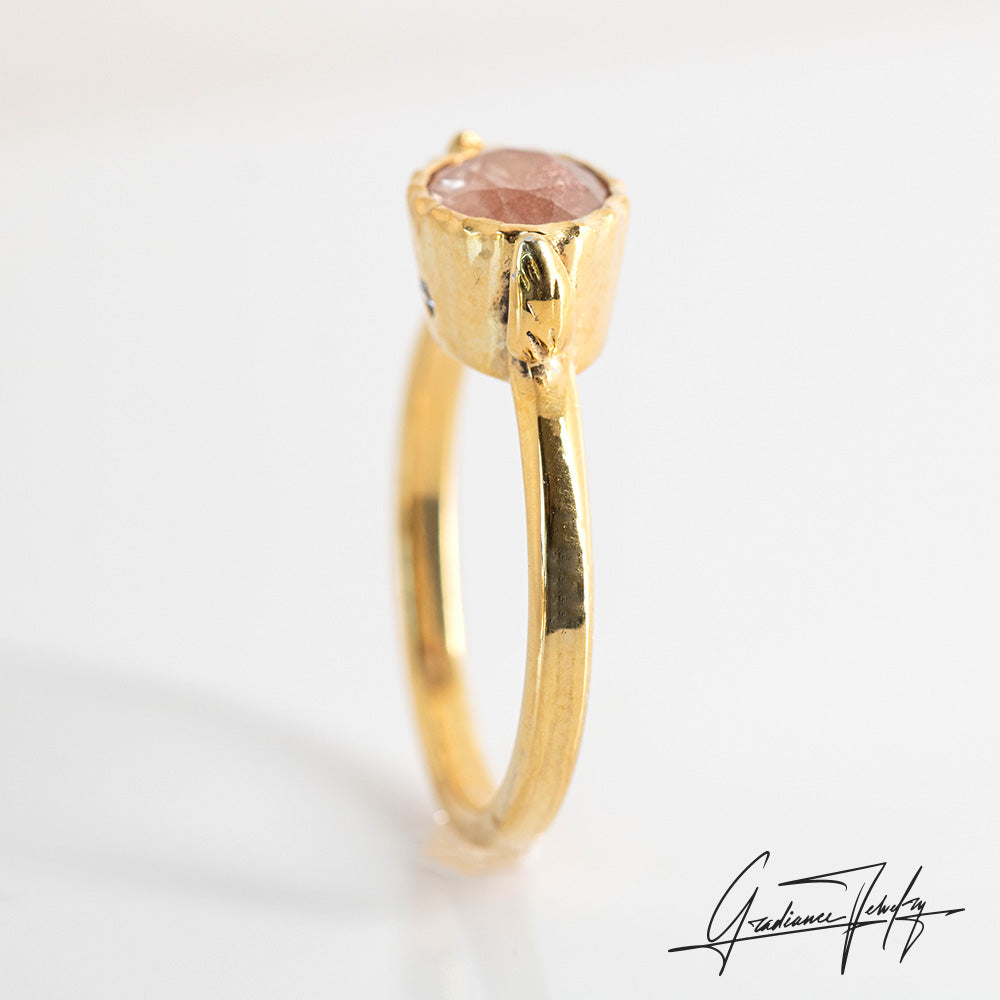 Gradiance Jewelry Sun Chaser Collection: women's 14KT yellow gold Rose ring featuring an oval Oregon Sunstone with schiller effect, accented by two diamonds and a leaf design, product shot from the side.